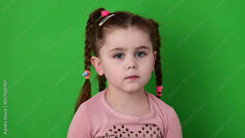 The girl corrects a blouse, the child on a green background. The girl corrects a blouse, the child on a green background.