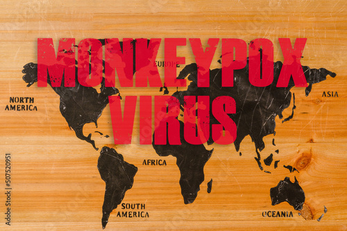 Monkeypox outbreak concept. Monkeypox is caused by monkeypox virus. Smallpox is a viral zoonotic disease. Virus transmitted to humans from animals.Inscription on the world wooden map. photo