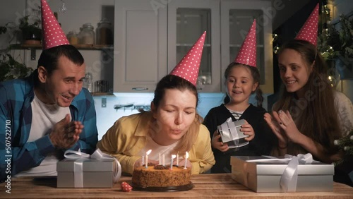 mam blows out candles. family celebrating birthday. cake with candles. mam blows out candles on birthday cake. Happy family at table in decorated kitchen during birthday celebration