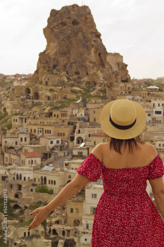 woman in a hat looking to the castle in cappadocia, turkey