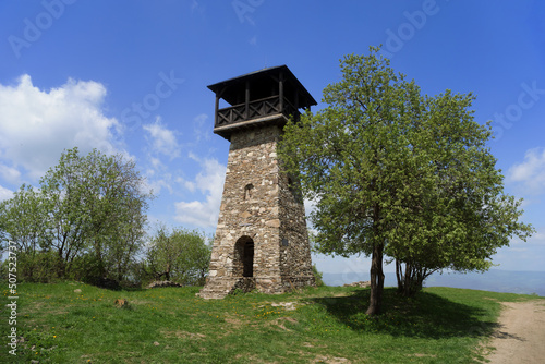 Lookout and observation tower on the top of hill, Martacky vrch, Zakopcie, Javorniky, Slovakia - landmark and monument building made of stone. Sunny spring weather and green tree. photo