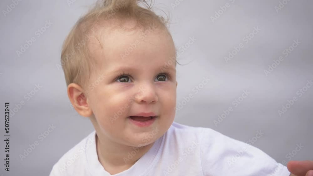 Beautiful smiling cute baby. Portrait of a happy child on a blue background. Funny happy baby smiling at the camera. adorable smiling baby with dark eyes in the nursery. The happiness of motherhood Beautiful smiling cute baby. Portrait of a happy child on a blue background. Funny happy baby smiling at the camera. adorable smiling baby with dark eyes in the nursery. The happiness of motherhood