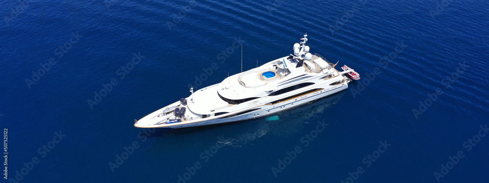 Aerial drone ultra wide panoramic photo of beautiful modern super yacht with wooden deck anchored in deep blue open ocean sea Aerial drone ultra wide panoramic photo of beautiful modern super yacht with wooden deck anchored in deep blue open ocean sea