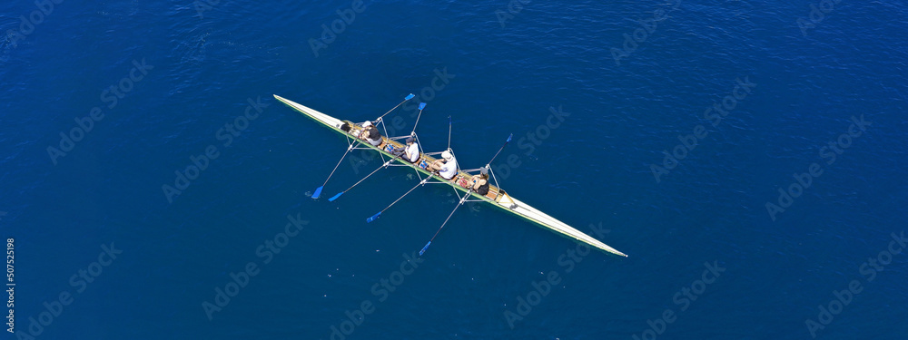 Aerial drone top ultra wide panoramic view of sport canoe rowing synchronous team of athletes competing in deep blue sea