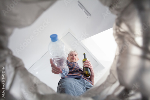 Male hand trowing a plastic bottle into a garbage bin