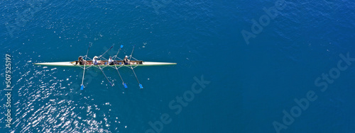 Aerial drone top ultra wide panoramic view of sport canoe rowing synchronous team of athletes competing in deep blue sea