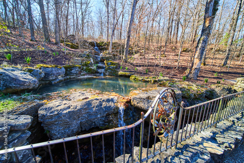 Fall forest with falls going into cavern next to metal railing photo