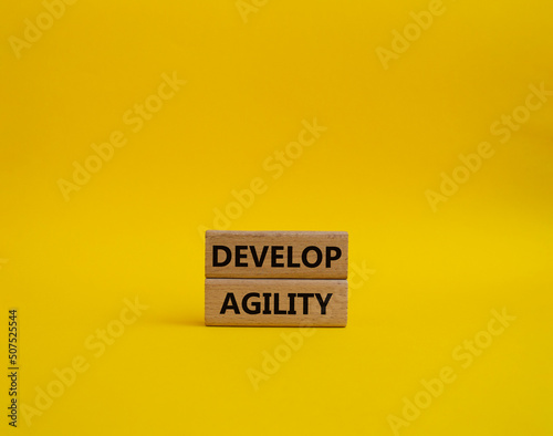 Develop agility symbol. Concept word Develop agility on wooden blocks. Beautiful yellow background. Business and Develop agility concept. Copy space