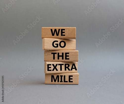 We go the extra mile symbol. Wooden blocks with words 'We go the extra mile'. Beautiful grey background. Business and 'We go the extra mile' concept. Copy space. photo