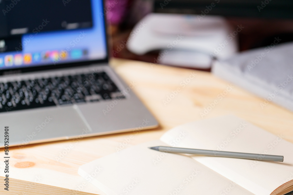 Home office with open laptop on blurred background. Notepad, pencil and laptop on a wooden table. Education business lifestyle concept. Soft focus. Copy space Home office with open laptop on blurred background. Notepad, pencil and laptop on a wooden table. Education business lifestyle concept. Soft focus. Copy space