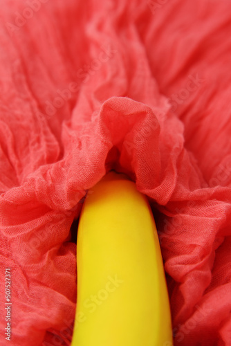 Sexy concept with banana on pink textile. Selective focus.