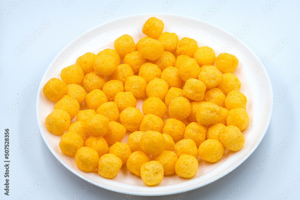 Selective focused cheese puff balls.  Pile of cheese balls isolated on white background. Plate full of cheese puff balls isolated