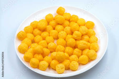 Selective focused cheese puff balls.  Pile of cheese balls isolated on white background. Plate full of cheese puff balls isolated