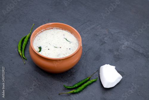 Fresh made Indian food, chutney, Coconut chutney in a bowl with raw coconut. Served with dosa, idli, vadai, Pongal. Selective focused home made coconut chutney in isolated white background. photo