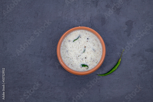 Fresh made Indian food, chutney, Coconut chutney in a bowl with raw coconut. Served with dosa, idli, vadai, Pongal. Selective focused home made coconut chutney in isolated white background.