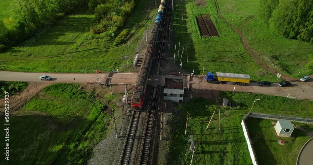 Railway crossing aerial view. Freight train. Sunlight before sunset.
