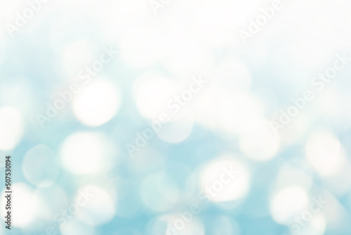 Bright abstract winter defocused background with shimmering sunspots in white and blue. Bokeh. Holiday festive concept. Copy space for text.