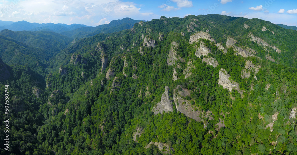 Aerial panorama of a rocky landscape - Raditavalley is populated by massive, eroded cliffs rising up from the beech forest. Summer season, Carpathia, Romania.