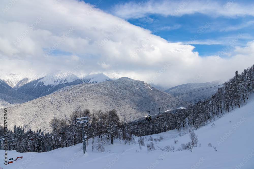 Beautiful winter landscape with snow covered trees and mountains peaks. Caucasus mountain view from Roza Khutor