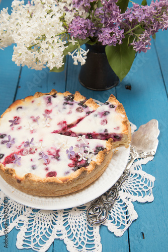 Homemade cake with berries and a bouquet of lilacs.