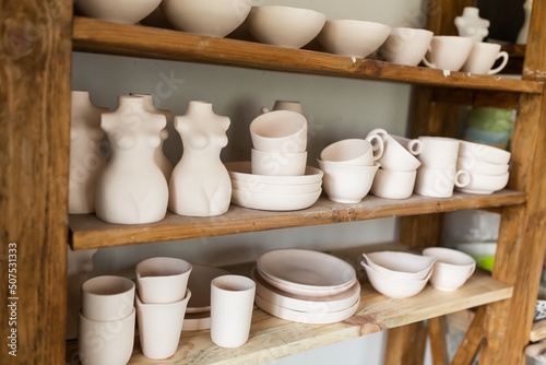Ceramic pots, plates and cups in clay on wooden shelves. Eco friendly pottery set handmade
