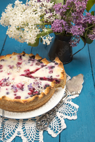 Homemade summer berry pie with a bouquet of lilacs.