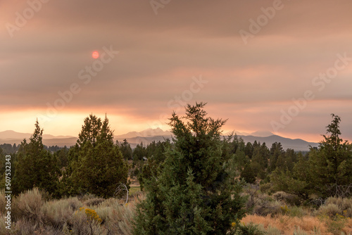 Wildfire smoke and sun over high desert landscape and mountains
