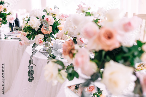 Wedding decoration table in the hall, floral arrangement. In the style vintage. Decorated dining table with flowers for guests and newlyweds, in peach-pink, pastel color.