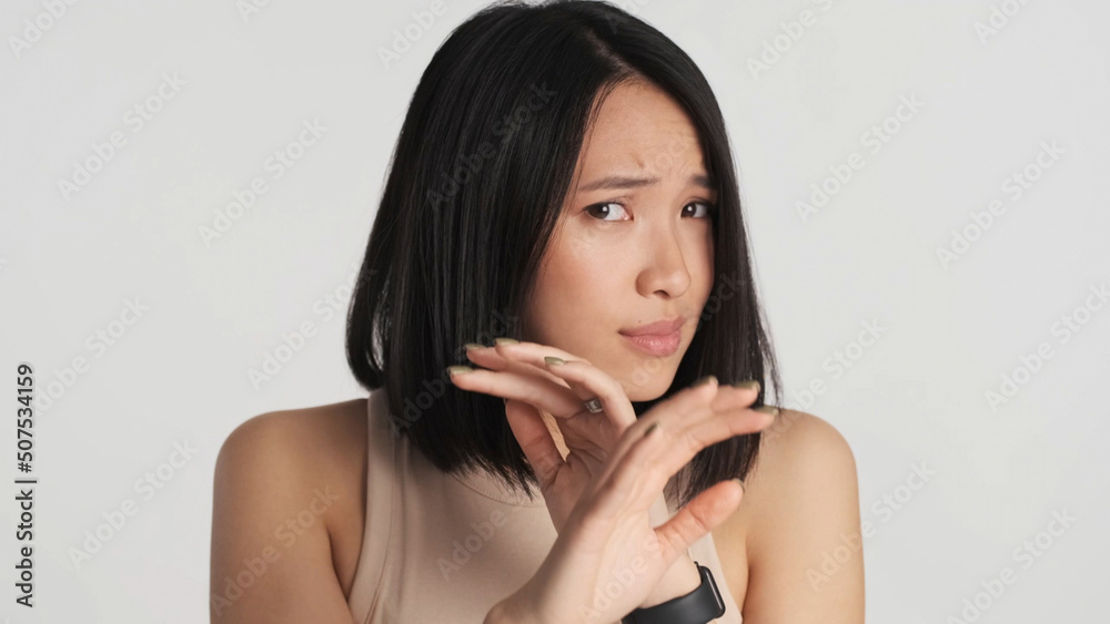 Scared Asian woman hiding face with hands afraid of something over white background. Human and phobia Scared Asian woman hiding face with hands afraid of something over white background. Human and phobia