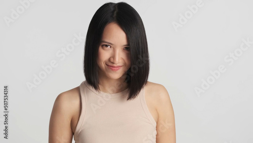 Photography Attractive Asian woman cunningly looking at camera over gray background