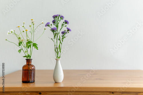 flowers in a vase. different flowers on a wooden table.