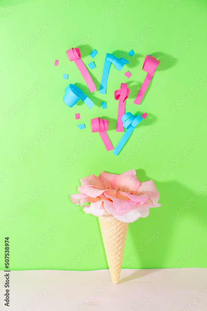 ice cream zone with pink flower above which confetti flies, creative summer party dessert design, green background with copy space