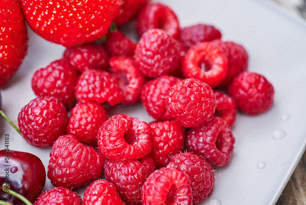 A plate of summer fruit. A close-up of raspberries on a plate. A plate of summer fruit. A close-up of raspberries on a plate.