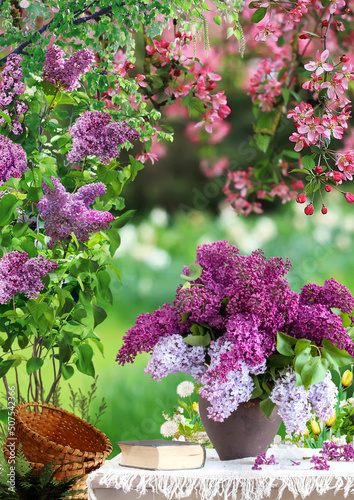bouquet of lilacs in a clay vase on a wooden table next to it lies a book against the background of beautiful spring bokeh