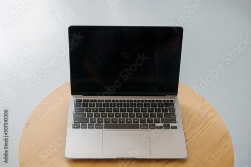 Thin laptop on wooden table and gray background.