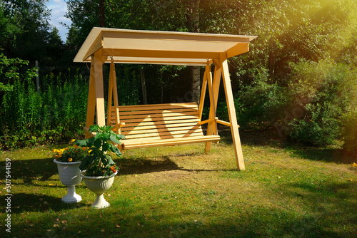 Wooden summer swing in the garden. Outdoor recreation. Landscape design of the infield. Build a garden swing with your own hands.