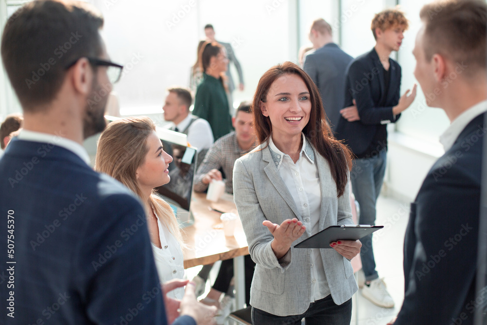 business woman talking to her colleagues standing in the office business woman talking to her colleagues standing in the office