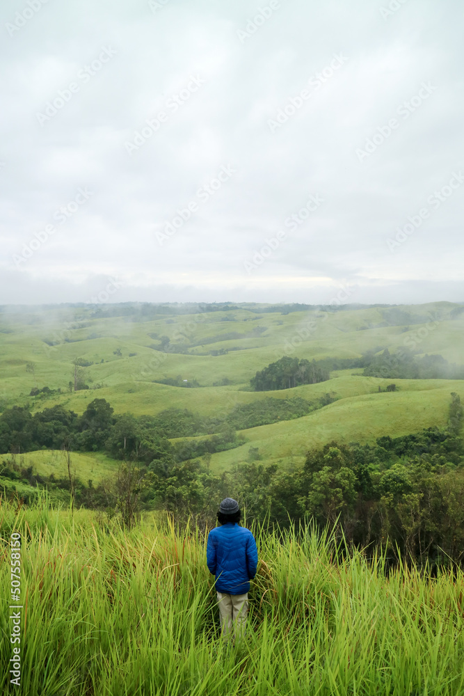 Man standing in middle of green hills. West Kalimantan.