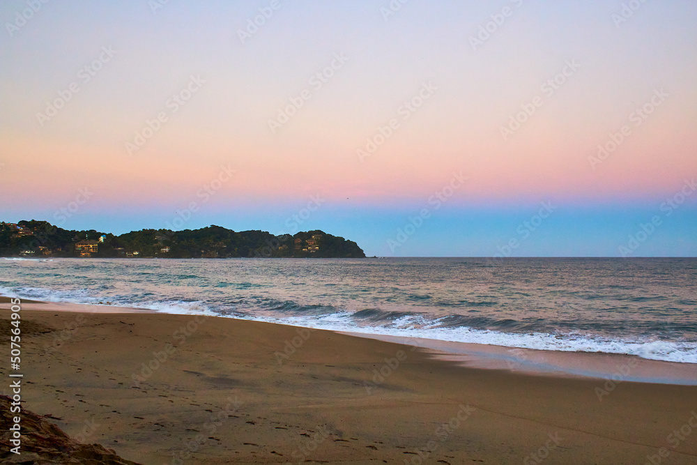 beach at sunrise with beautiful sky  with orange and blue colors and waves in sayulita nayarit