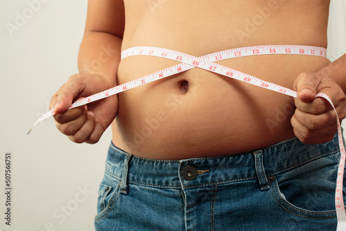 fat man check out body overweight abdomen his belly with in hand measuring tape photo