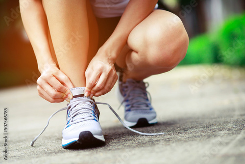 Running shoes. close up female athlete tying laces for jogging on road. Runner ties getting ready for training. Sport lifestyle. copy space banner.