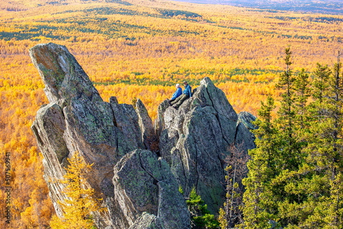 Mature tourists posing on the rocks of the mountain round hill on the Alabia ridge in the Ural mountains on an autumn sunny day. photo