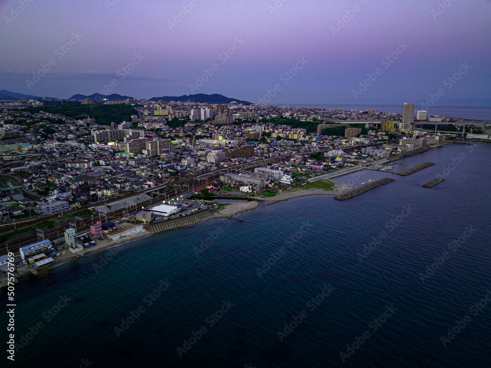 Aerial view of post-sunset glow over coastal town on point