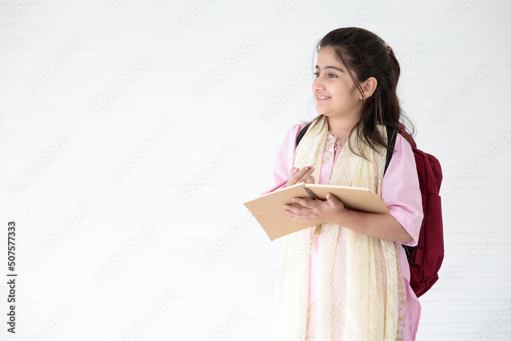cute Indian girl smiling and writing on notebook for learning, education concept cute Indian girl smiling and writing on notebook for learning, education concept