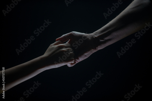 Helping hand outstretched, arm on salvation. Close up strong hand. Two hands, helping arm of a friend, teamwork. Rescue, power, helping gesture or hands. Black background.