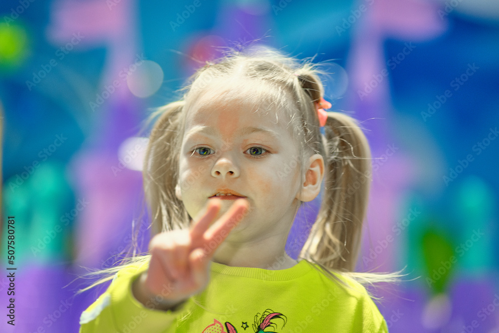 A cute little girl with ponytails on her head is playing in a children's town.