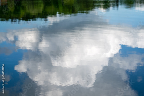 Spiegelung des Waldes und einer riesig großen Wolke im Stille Wasser eines Sees