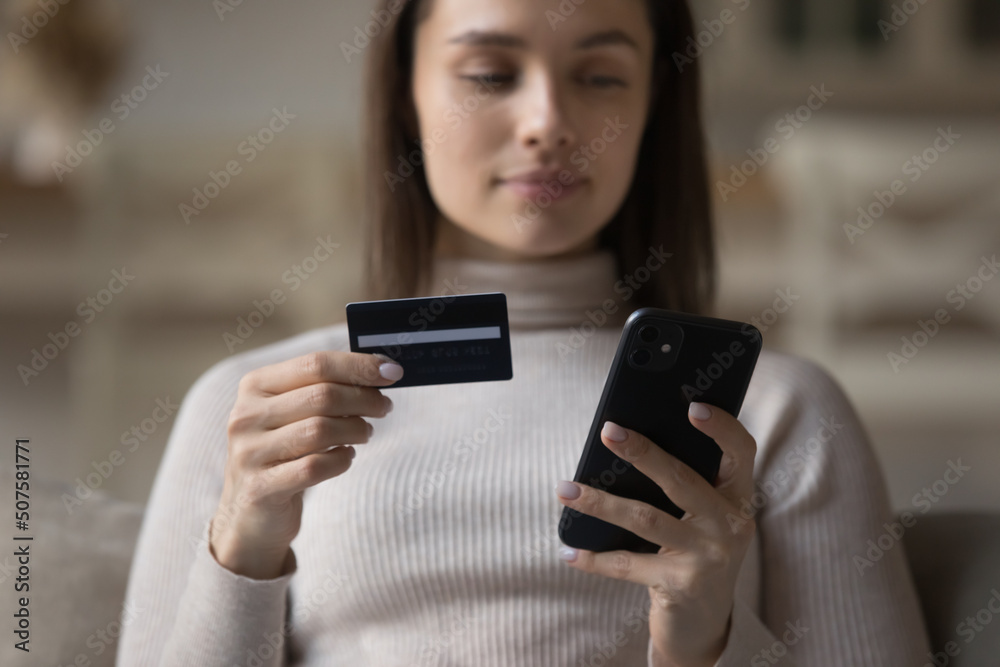 Bank customer girl using mobile phone, holding credit card, shopping on Internet stores with virtual payment app, making international transfer, transactions, paying for online purchase. Hands closeup Bank customer girl using mobile phone, holding credit card, shopping on Internet stores with virtual payment app, making international transfer, transactions, paying for online purchase. Hands closeup