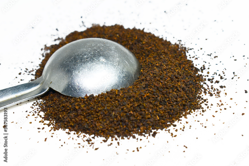 Black Tea Powder or dust with or without green leaf and served hot chai in a cup. Black Tea powder in the spoon isolated on white background 