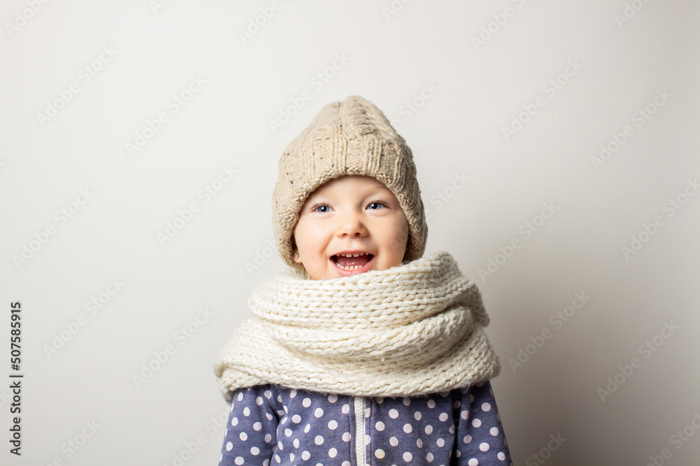 beautiful little baby in a hat is surprised on a light background. Concept of children's emotions, winter, shopping beautiful little baby in a hat is surprised on a light background. Concept of children's emotions, winter, shopping